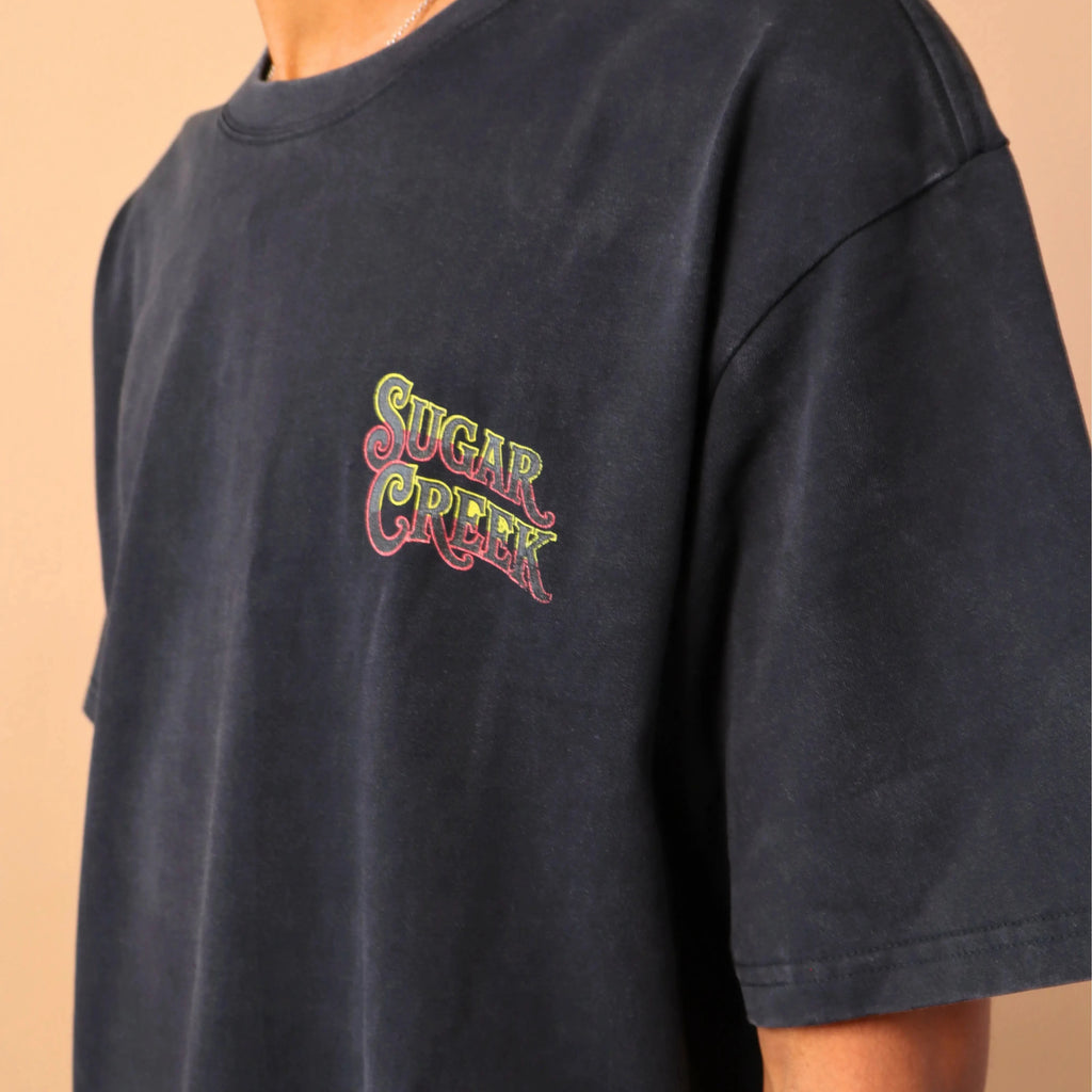 Person wearing a navy blue t-shirt with colorful text design on a beige background