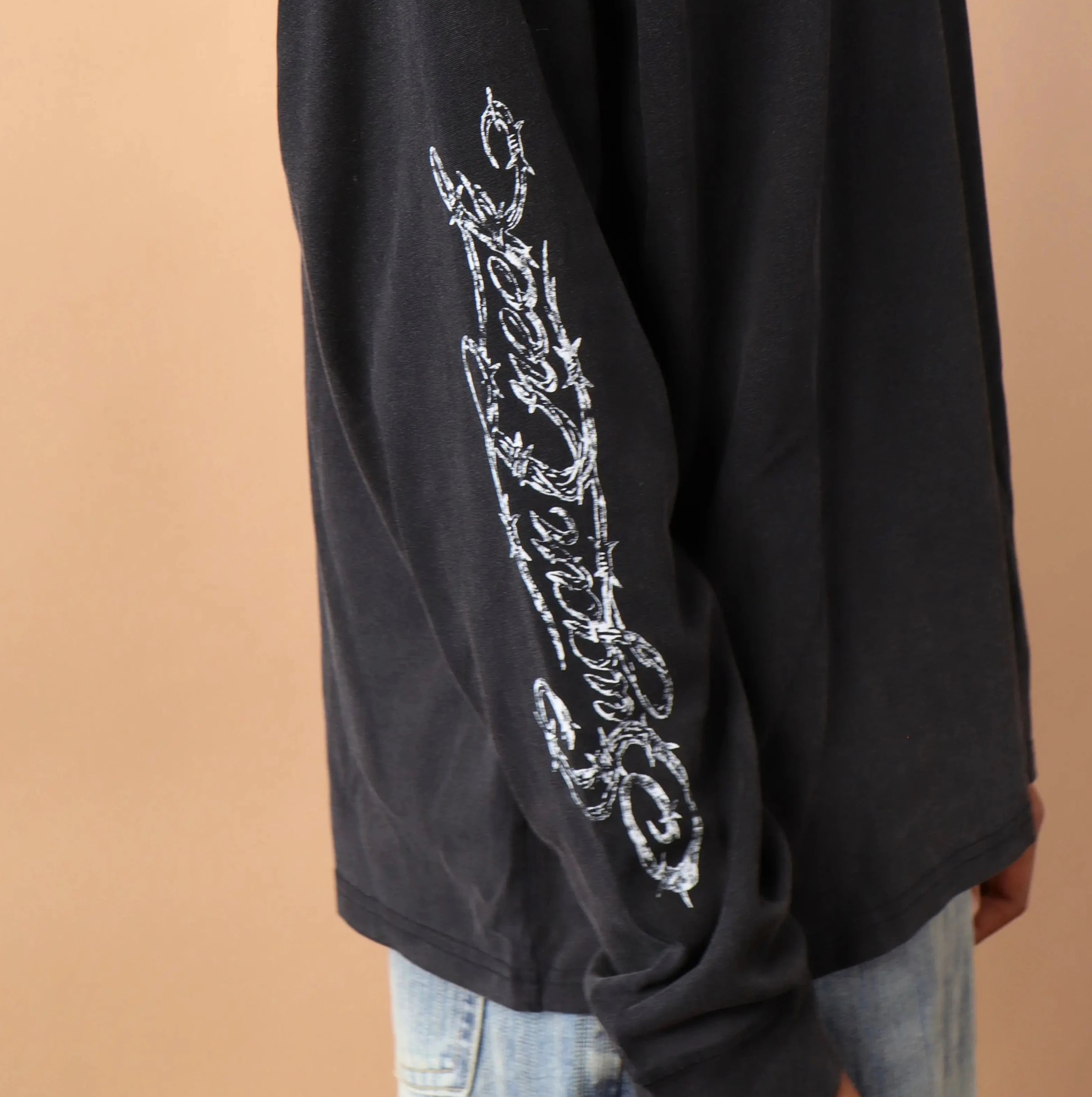 Black long-sleeve shirt with white text design on a beige background