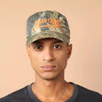 Person wearing a camouflage cap with text on a beige background
