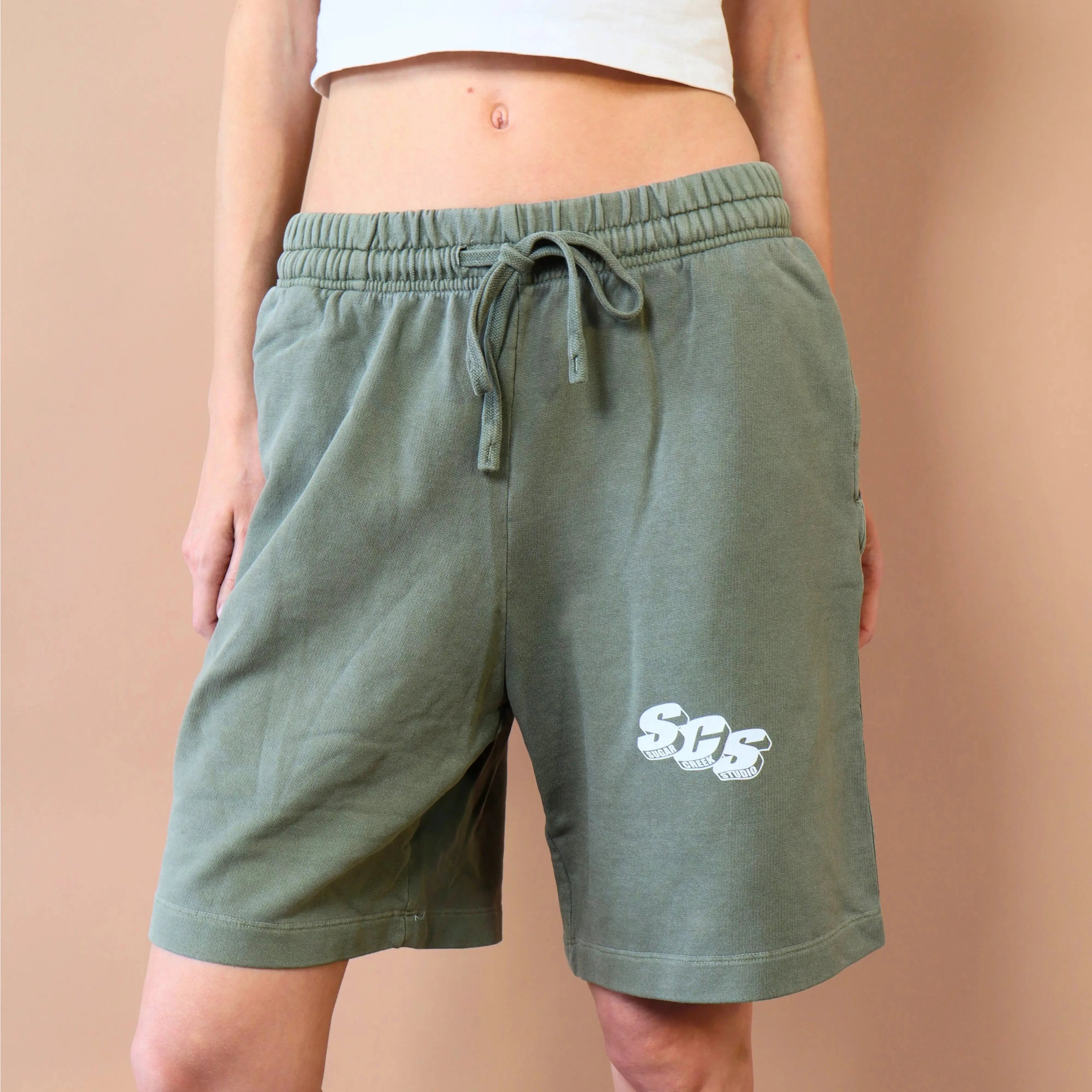Person wearing green shorts with a logo on a beige background