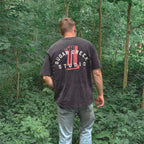 Man wearing a black t-shirt with 'Sugar Creek Studio' logo walking through a forest.